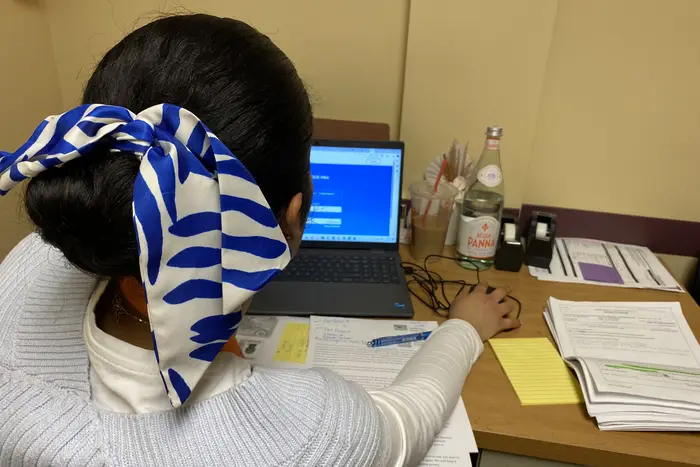 A woman wearing a white and blue hair bow toggles through the city's municipal ID website.